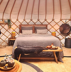 Het bed van Yurt Venus opgemaakt met aardse bruintinten in een stijlvol interieur.