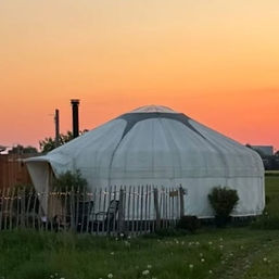 Yurt Venus bij zonsondergang onder een warme oranje lucht in de Achterhoek.