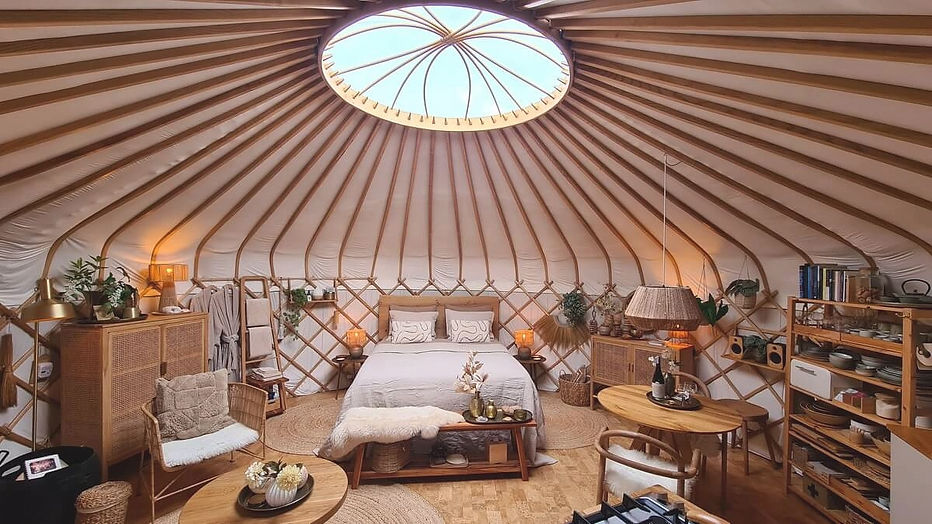 Slapen in een yurt bij Celestial Living, met royaal bed dat zorgt voor rust in een omhullende ronde ruimte.