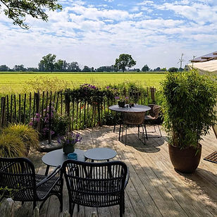 Privéterras van Yurt Orion met vrij uitzicht over het groene landschap en veel ruimte rondom de yurt.