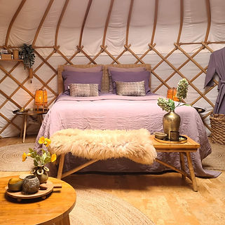 Koppeling naar Yurt Orion: bed opgemaakt met paars en vintage-roze bedlinnen.