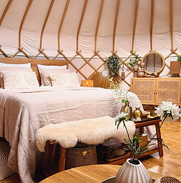 Yurt Sirius met zandkleurig beddengoed - rustige sfeer in een lichte yurt met zachte tinten.