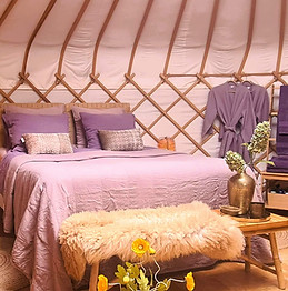 Een kleurige slaapplaats in Yurt Orion - bed in een ronde ruimte met sfeer en comfort.