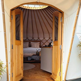 Open deuren van yurt Sirius – een inkijk in een omgeving vol rust en eenvoud maar met comfort