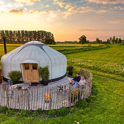 Dronebeeld van Yurt Venus met terras in warm avondlicht en veel vrije ruimte rondom de yurt.