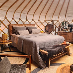 Het bed van Yurt Venus is opgemaakt met taupe en bruine tinten in een warm en aards interieur.