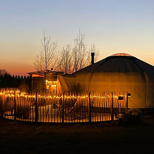 Yurt Sirius met verlicht terras tijdens de avondschemering.
