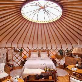Yurt Sirius van binnen toont een stijlvol interieur met bed, zithoek en ronde ruimte voor een yurtverblijf.
