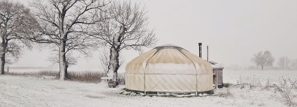 Achterzijde van Yurt Orion in een wit besneeuwd en stil winterlandschap.