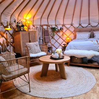 Yurt Sirius interieur vanaf de deur met bed en zithoek, lichte serene stijl en duurzame keuzes in materialen.