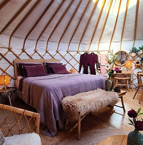 Yurt Orion bed met kleurrijk linnen beddengoed, uitnodigend om vroeg te gaan liggen en diep te slapen.