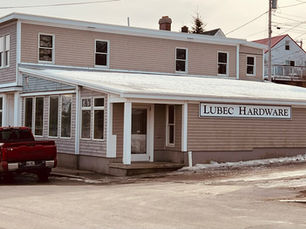 Exterior of Lubec Hardware in Lubec, Maine, a beige building with a “Lubec Hardware” sign and a red pickup truck parked outside.