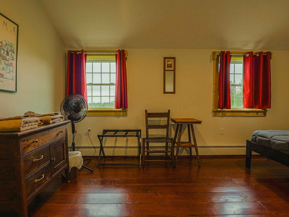 Bedroom with dresser, table, chair, and fan in the corner