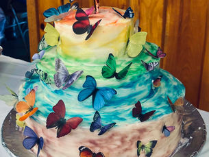 Three-layer memorial cake decorated with colorful butterflies and pastel icing at Sineidin’s memorial gathering at American Legion Post 65.