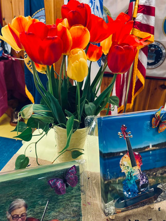 Tulips, violin-themed memorial items, and butterfly decorations displayed on a remembrance table at the Legion Hall.