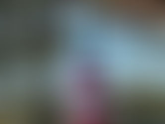 Red and white striped buoy hanging from a porch roof, dusted with snow and icicles, with evergreen trees and blue winter sky behind it.