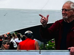 Bill stands beside the West Quoddy Station finish-line banner during the Bay of Fundy International Marathon, greeting runners and visitors near the finish area.