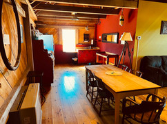 Interior dining and kitchen area of the Station House with wood floors, red and yellow walls, and a large wooden table.