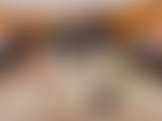 Rows of numbered five-gallon buckets arranged on the floor of a wood-paneled hall during an indoor ice fishing derby, with guests socializing in the background at American Legion Post 65.