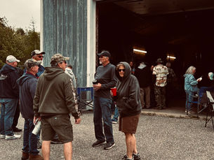 Guests stand and chat outside a large garage during Tina’s annual birthday party in Lubec, Maine, on a cool June afternoon.