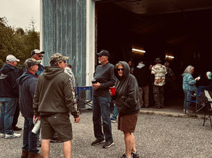 Guests stand and chat outside a large garage during Tina’s annual birthday party in Lubec, Maine, on a cool June afternoon.