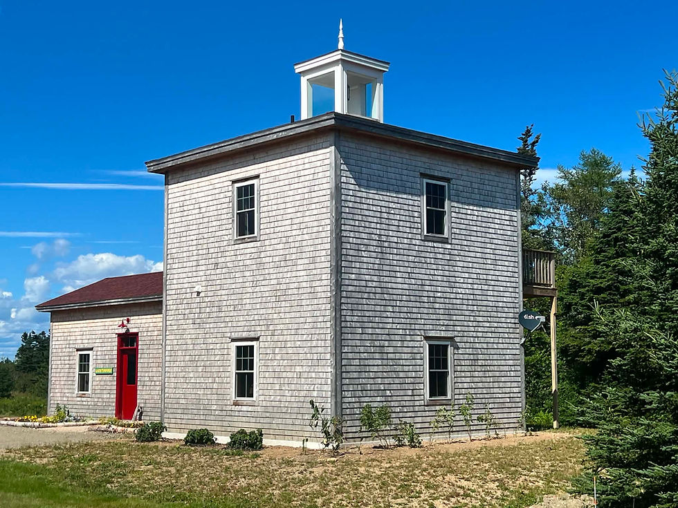 Cedar-shingled Clark’s Folly Lighthouse with its cupola and red entrance door at West Quoddy Station.