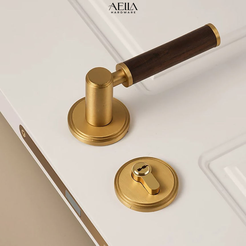 มือจับประตูสีทองพร้อมด้ามไม้ พร้อมป้าย AELLA HARDWARE บนบานประตูสีขาว