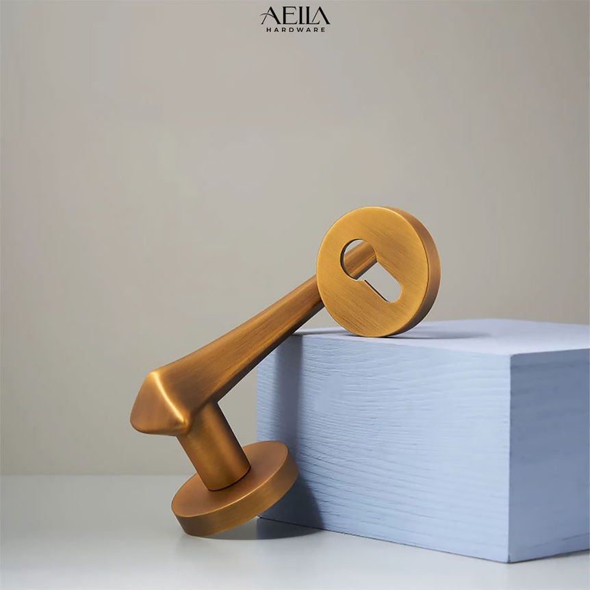 มือจับเฟอร์นิเจอร์สีทองวางอยู่บนกล่องสีฟ้า AELLA HARDWARE สวยงามอย่างมีสไตล์