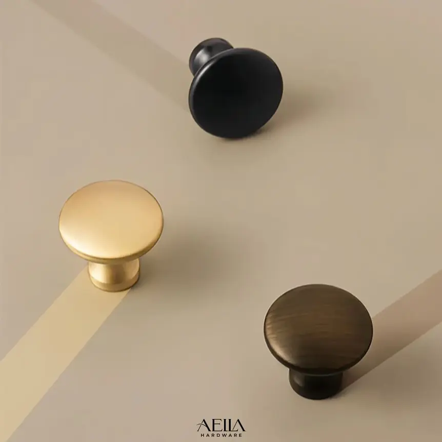 มือจับเฟอร์นิเจอร์สีดำและทองเหลืองวางบนพื้นผิวสีเทาอ่อน AELLA HARDWARE