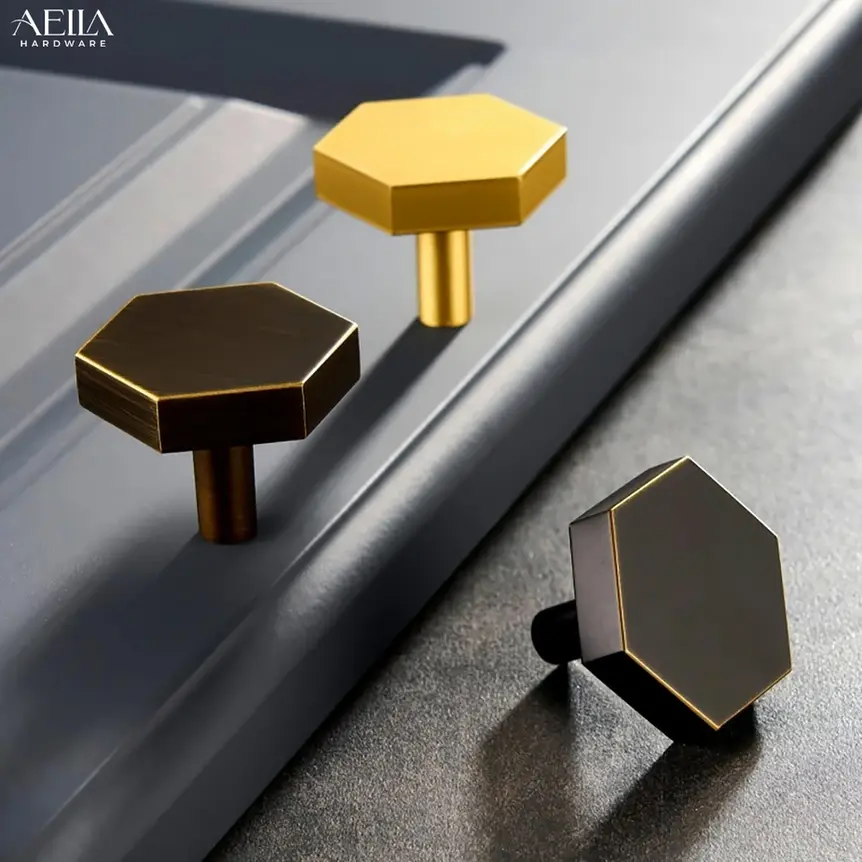 AELLA HARDWARE, hardware knobs display, บานพับข้อเสือสีเงิน with grey cabinet background.