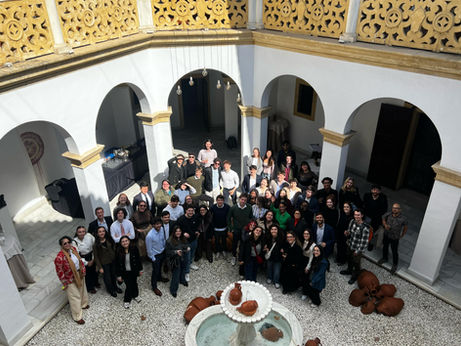 Group picture of students and professionals smiling, in an Andalusian patio