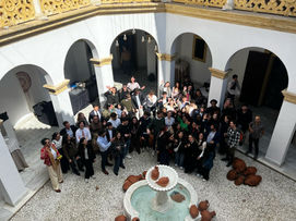 Group picture of students and professionals laughing, in an Andalusian patio