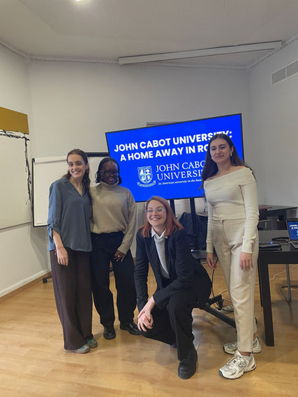 Fours students in front of a screen presenting their college, John Cabot University