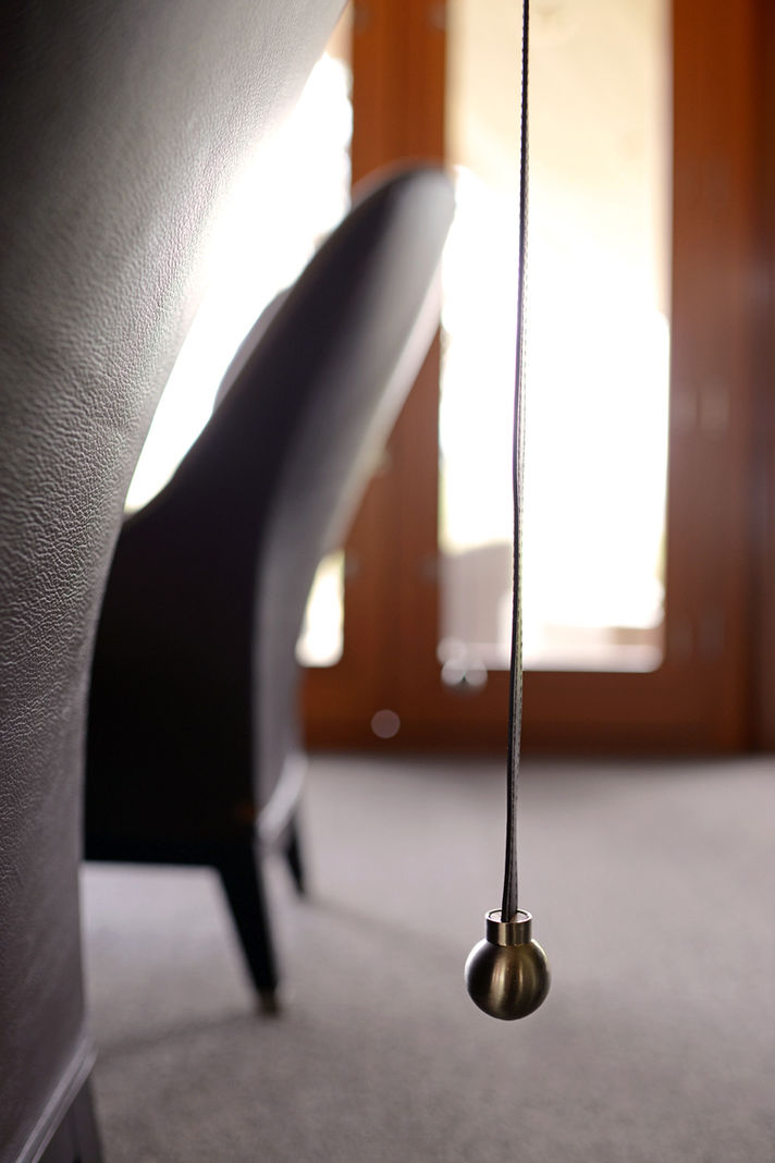 Gina Taro Interior design photograph of a metal pendulum hanging in a room with a chair.