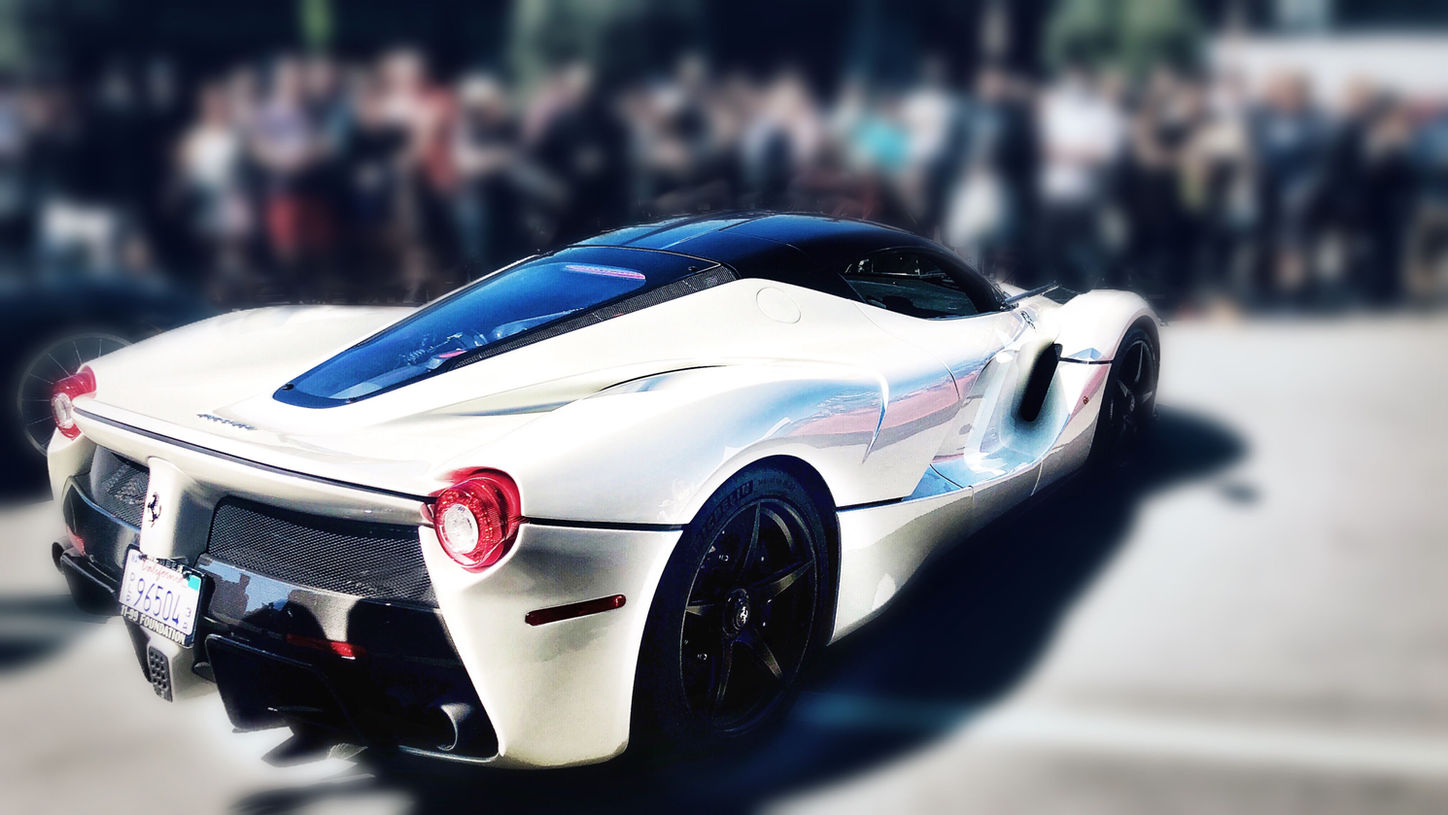 White Ferrari LaFerrari parked in front of a crowd during Monterey Car Week - automotive photography by Gina Taro
