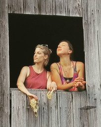 two woman standing in an open barn window