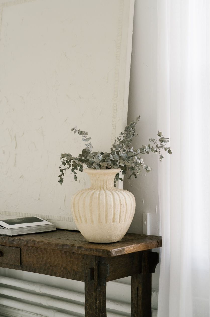 ceramic vase with eucalyptus styled on a rustic wooden side table