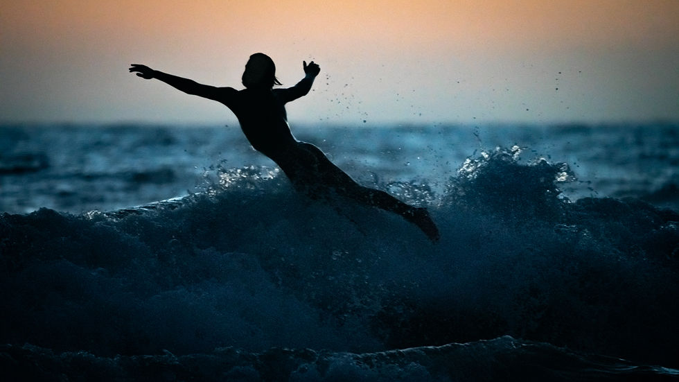 A surfer catching a wave and leaping off his board over the wave , Manhattan beach