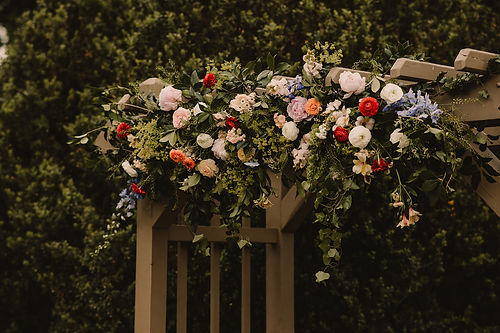 Floral arch with roses, ranunculus, and greenery for outdoor wedding ceremony at Rust Manor House in Leesburg Virginia