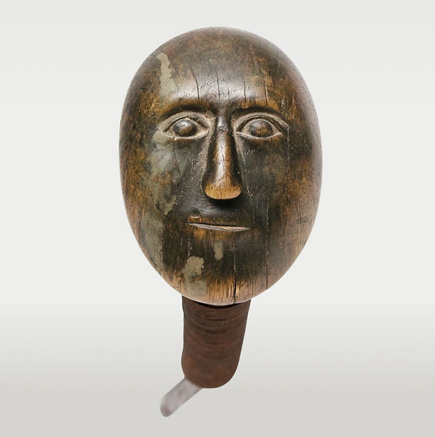 Frontal close-up of the carved human visage on an 18th-century Iroquois crooked knife featuring blue-green pigment and steel wire. Ex: Ned Jalbert and Adelaide de Menil collections.