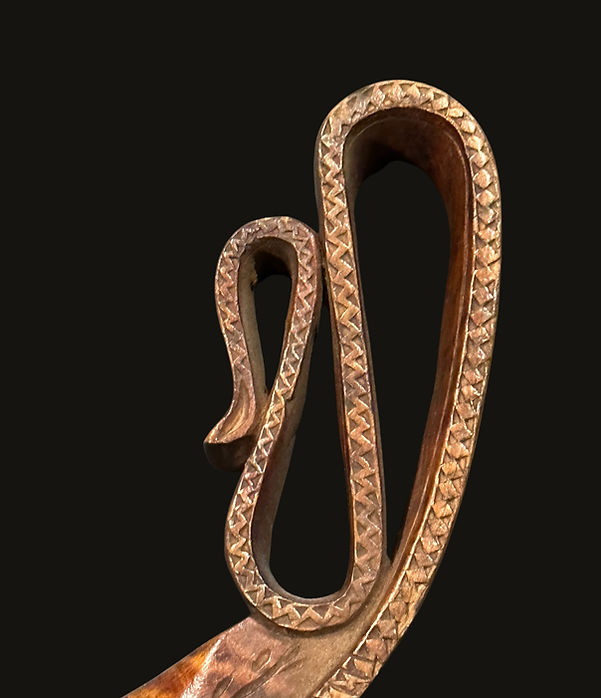Close-up of a Penobscot crooked knife (mocotaugan) handle from circa 1850–1880, featuring complex ribbon-work carving representing an uncurling vine.