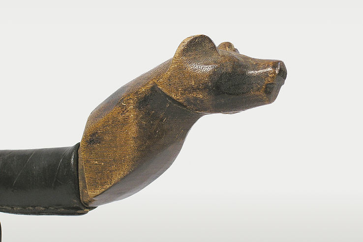 Close-up side view highlighting the multi-plane chisel and knife facet technique used to sculpt the cranial structure and muzzle of a Mesquakie bear effigy crooked knife.