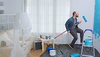 Man playfully paints wall, blue paint, Home improvement project