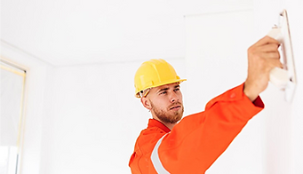 Worker sanding wall with power tool