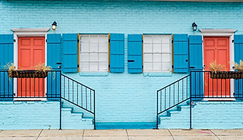 Two coral doors, blue shutters, light blue brick building