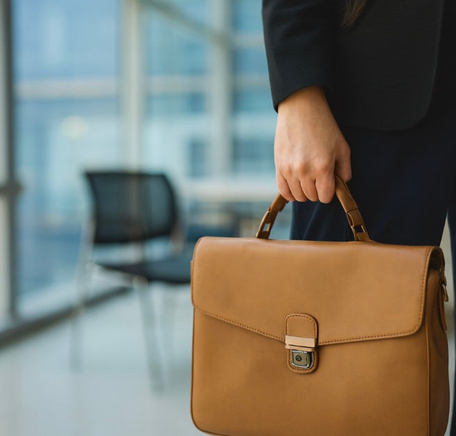 a woman's hand holding a briefcase in an office space