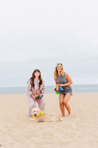A GIF of two women jumping on the beach throwing Skinny Dipped products in the air in a celebratory manner
