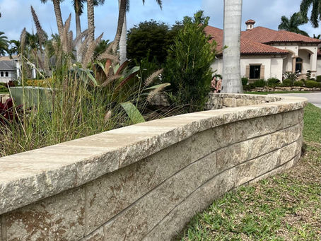 Decorative retaining wall framing a landscaped flower bed with pavers and plants,