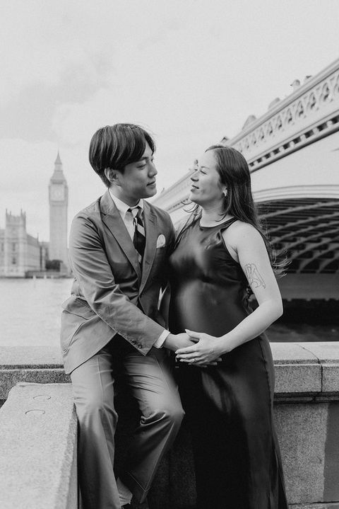 a man in a suit and tie sits next to a pregnant woman