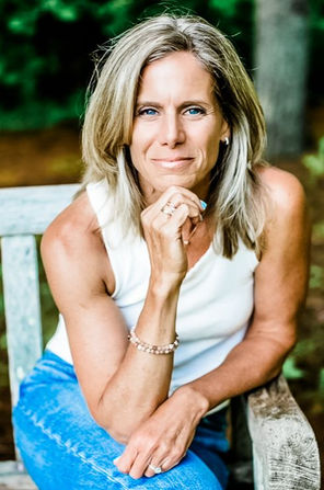 A woman sitting on a wooden bench leaning forward with her hand on her chin